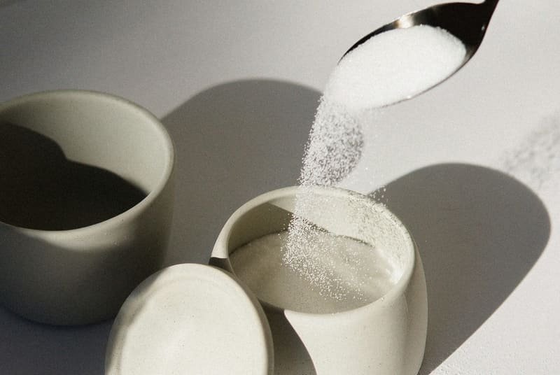 zdjęcie cukru przesypywanego łyżeczką do cukiernicy