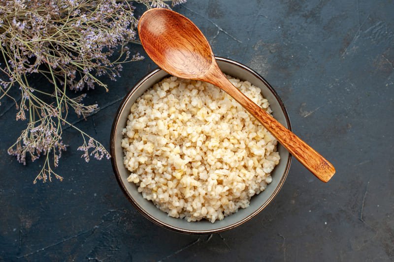 zdjęcie kaszy owsianej z miseczce z łyżką w otoczeniu suszonych kwiatów