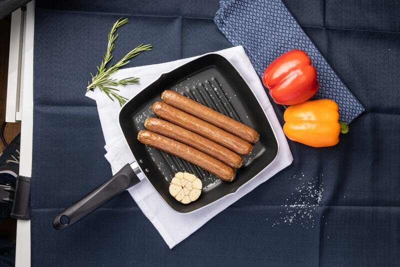 parówki zdjęcie parówek ułożonych obok siebie na patelni grillowej, obok dwie papryki