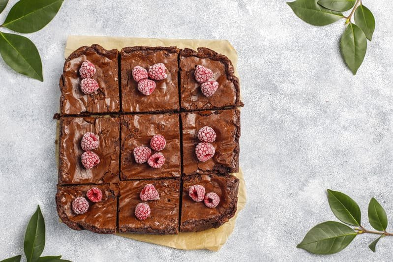 Bezglutenowy murzynek – puszyste ciasto czekoladowe pokrojone na kawałki, udekorowane malinami