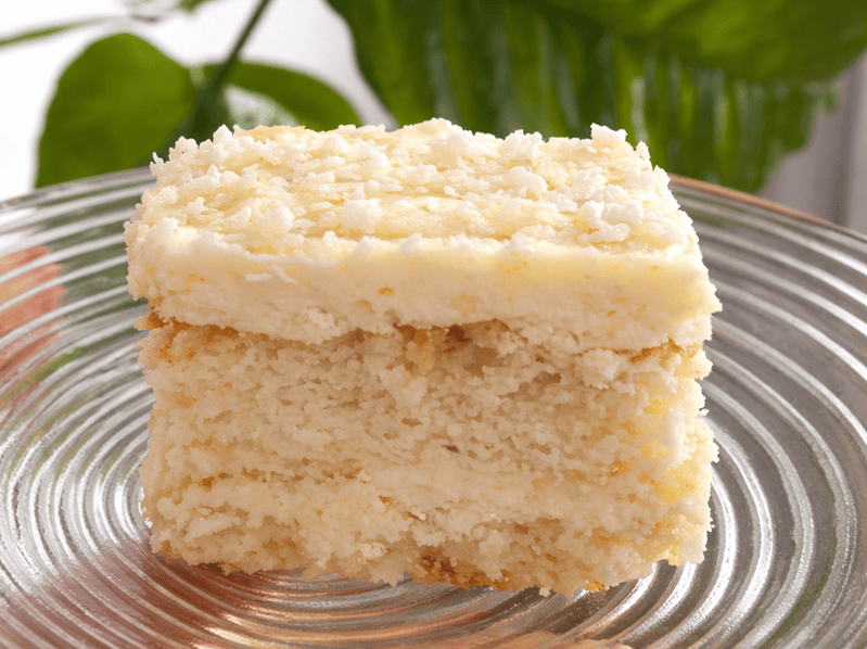 rafaello (1) (1) Kawałek bezglutenowego ciasta rafaello na szklanym talerzu – kokosowy deser z kremową warstwą i wiórkami kokosowymi, podany w naturalnym świetle.