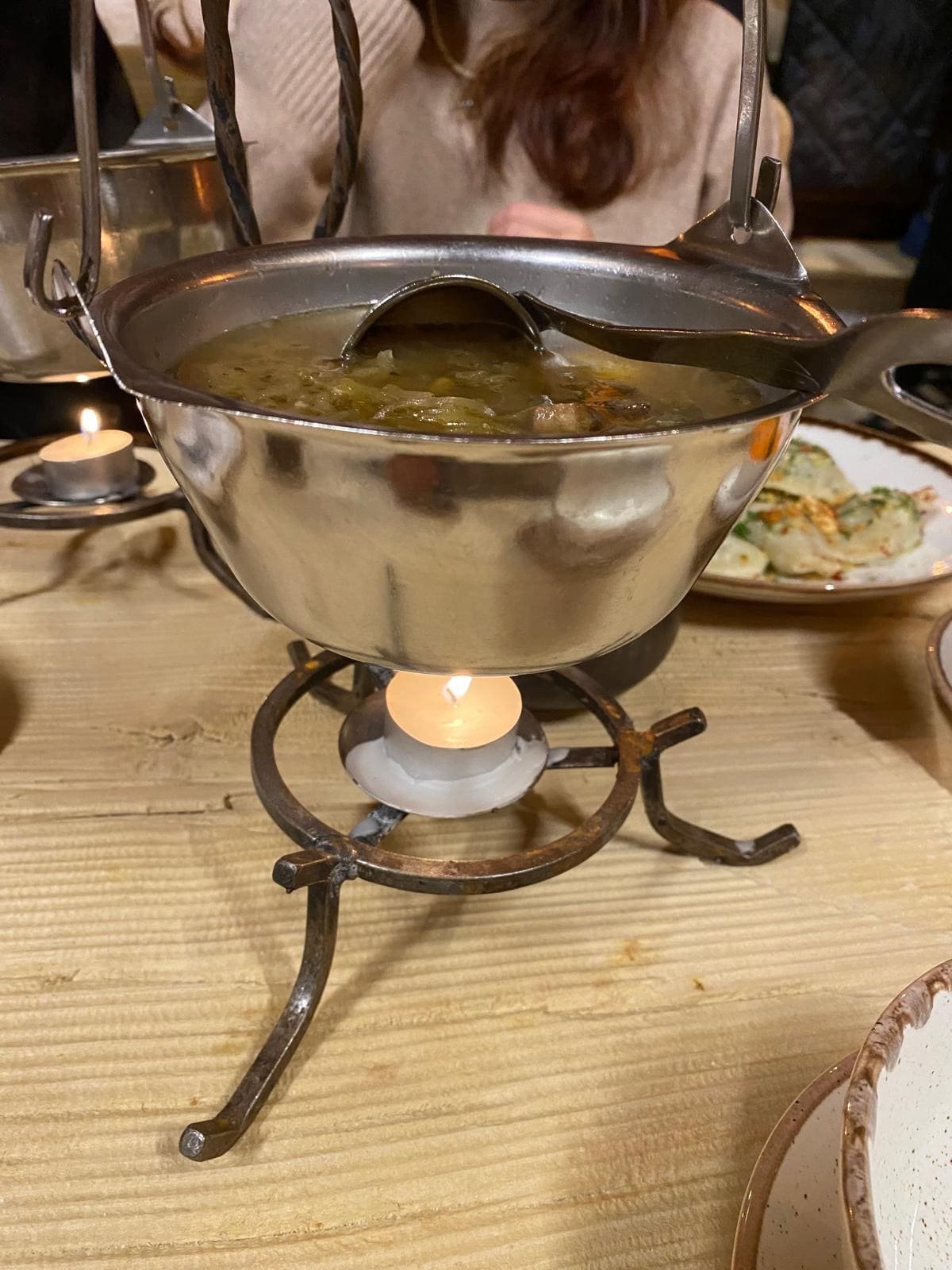 kwaśnica bezglutenowa podana w metalowym naczyniu z chochlą na tle stołu z jedzeniem 
