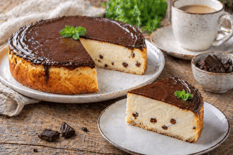 Sernik bez mąki z polewą z ciemnej czekolady, wilgotny i puszysty, z kawałkiem na talerzu, podany w rustykalnym domowym stylu