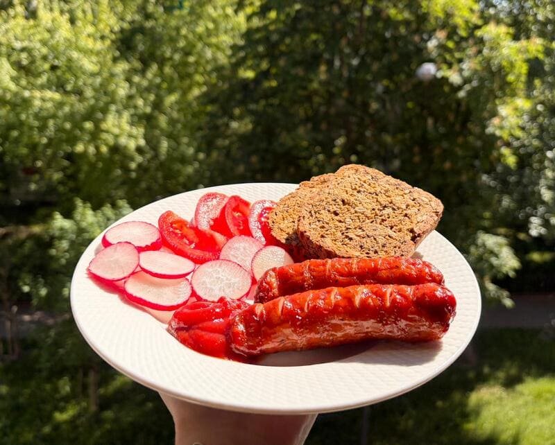 Grillowane kiełbaski podane z kromką bezglutenowego chleba owsianego i świeżą rzodkiewką.